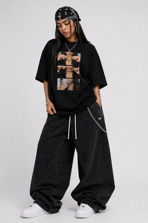 Person wearing a black oversized t-shirt with graphic designs and black pants on a white background